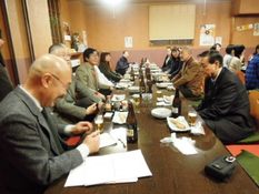 参加された方々が机を挟んで座り、食事や会話を楽しんでいる様子