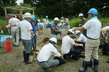 市役所若手職員に土のう作りの指導